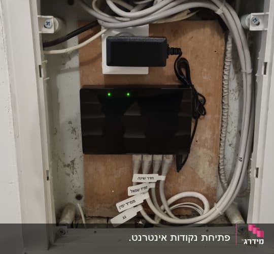 ארון תקשורת ביתי מסודר עם מתג רשת וכבלים מסומנים במדבקות